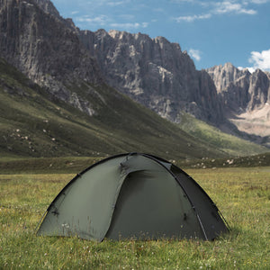 Pine green TFS Stars 2 Pro pitched on grass beneath rocky mountain cliffs.