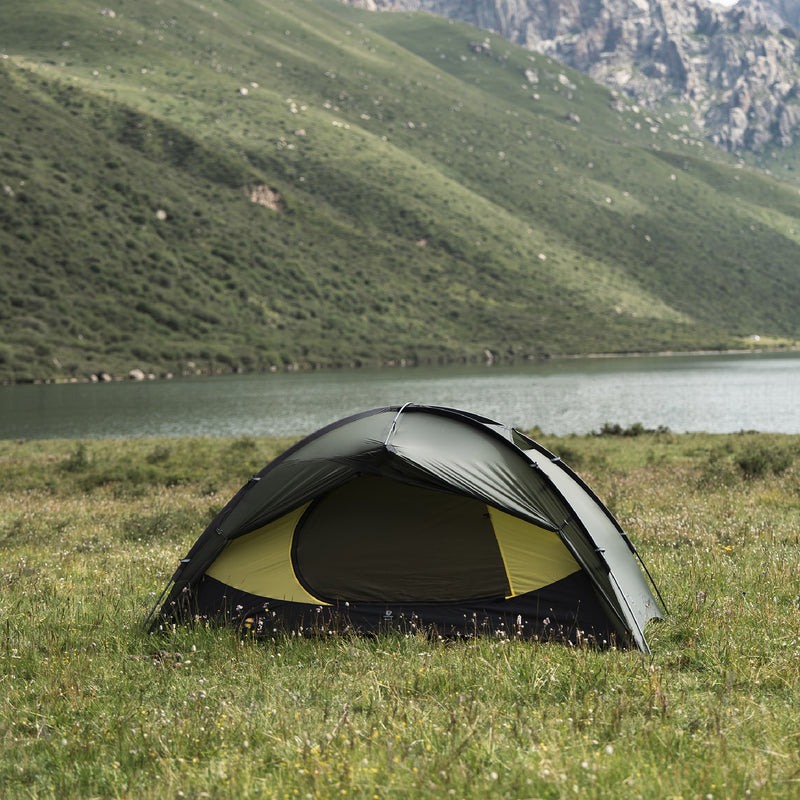 Front view of a pine green TFS Stars 2 Pro with the rainfly door open at a lakeside campsite.