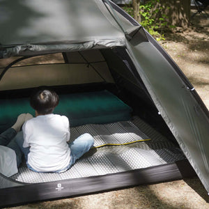 Inside a TFS Stars 4 tent in Holy Green, a camper sitting on a sleeping mat with a mesh floor.